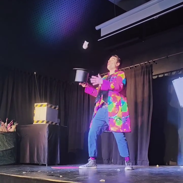 Zauberauftritt im Theater Ein magischer Auftritt mit einem Kinderzauberer in buntem Kostüm und einem Zylinderhut.